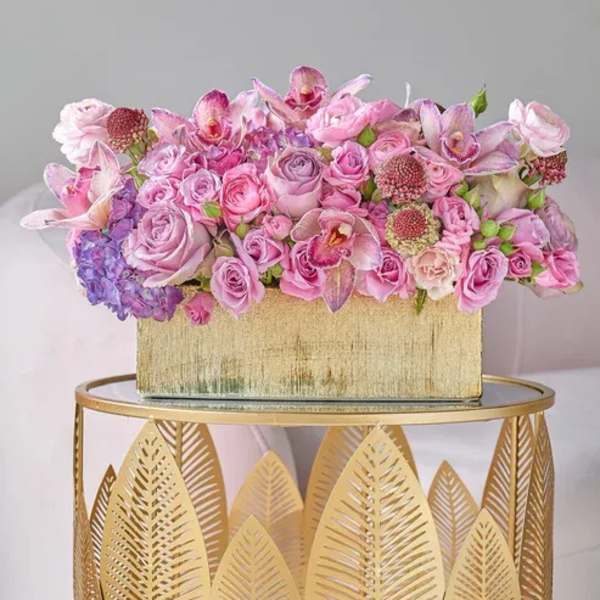 Pink and lavender floral arrangement in a gold rectangular box