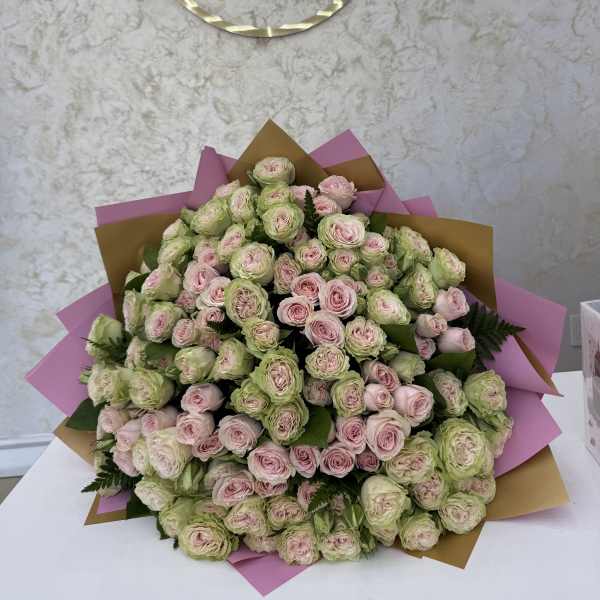 Large bouquet of pale pink and green roses wrapped in pink and gold paper
