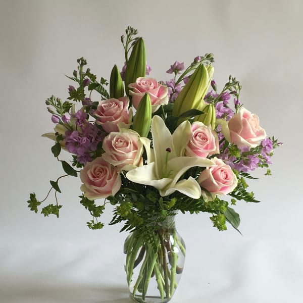 Pink roses and white lilies in a clear glass vase
