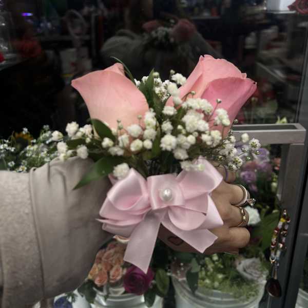 Pink rose boutonniere with baby's breath and a satin bow