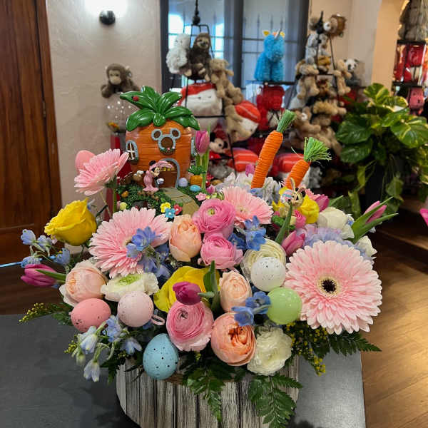Pastel flower arrangement with a decorative carrot house and Easter eggs