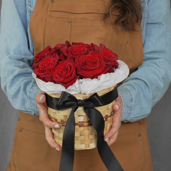 Basket of red roses wrapped with white paper and a black ribbon