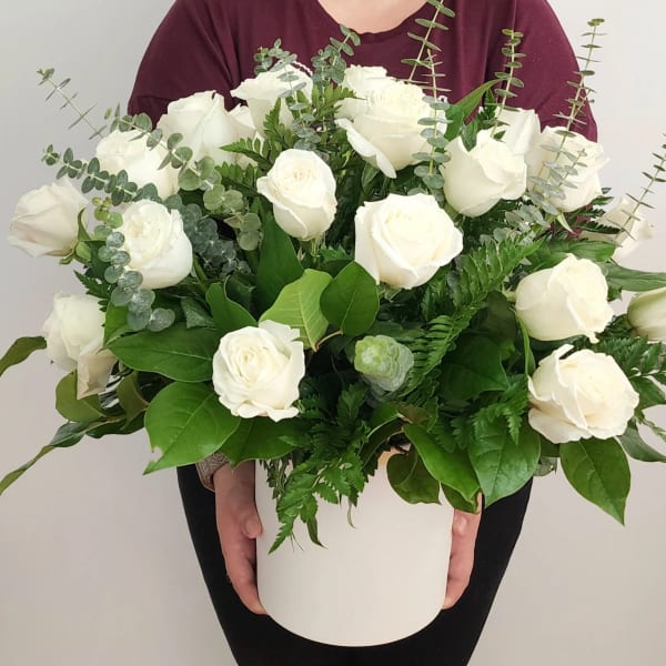 White roses in a white hatbox with eucalyptus and greenery