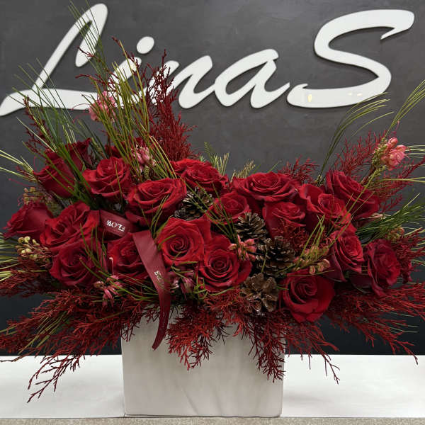 Red rose arrangement in a white box with pinecones and ribbon