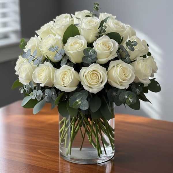 White rose bouquet in a clear glass vase with eucalyptus accents