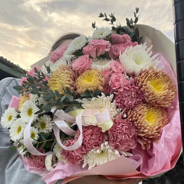 Large bouquet of pink roses, white chrysanthemums, and yellow blooms wrapped in pink paper