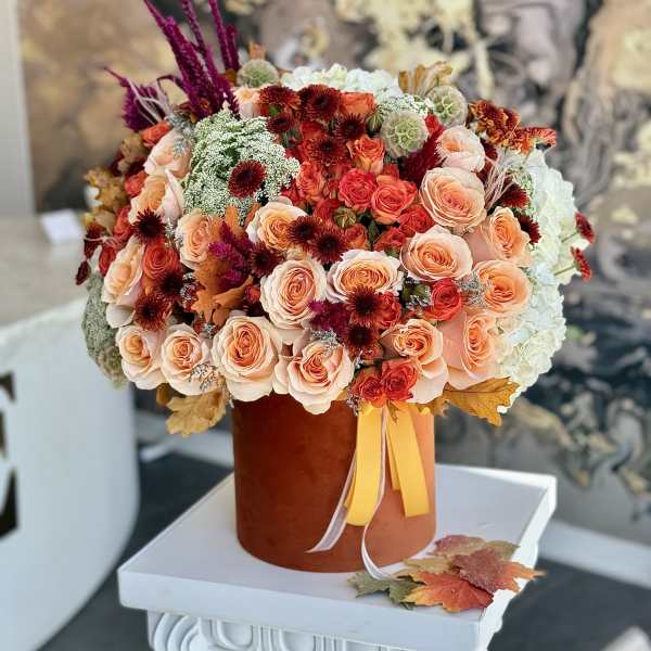 Peach and red rose bouquet in a brown hatbox with ribbon