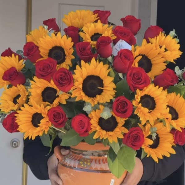 Bouquet of red roses and sunflowers in an orange vase