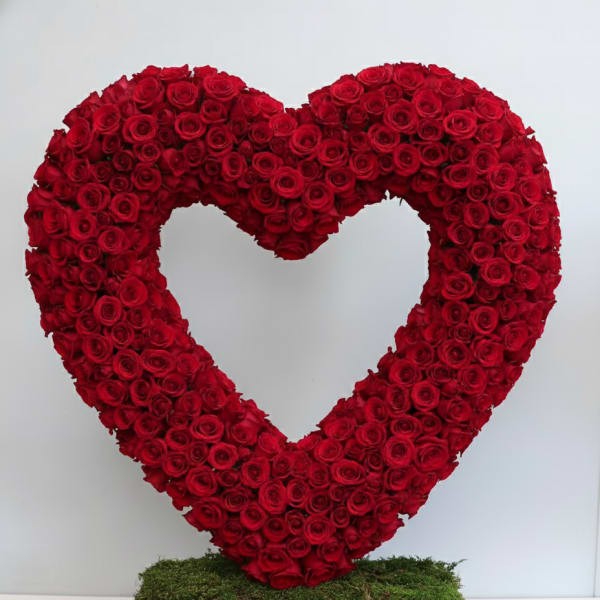 Large open heart of red roses on a moss-covered rectangular base