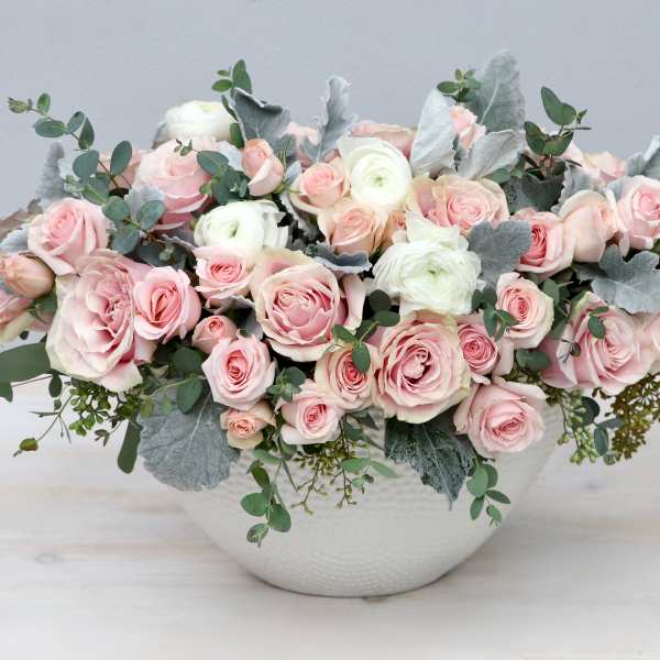 Low white bowl arrangement of blush pink roses and white ranunculus