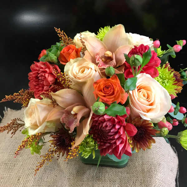Mixed bouquet with roses, orchids, and chrysanthemums in a low container