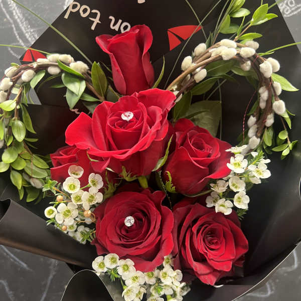 Bouquet of red roses with white filler flowers in black wrapping