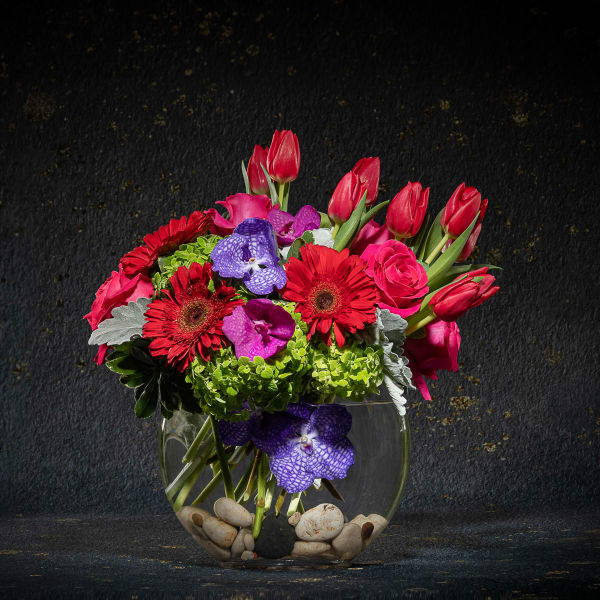 Bright mixed bouquet in a round glass vase with stones
