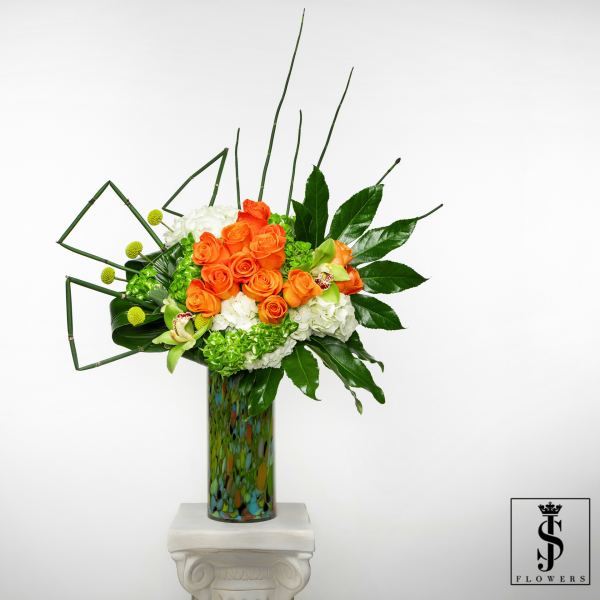 Orange roses and white hydrangeas in a tall patterned vase