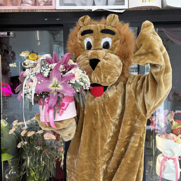 Lion mascot holding a pink flower box bouquet