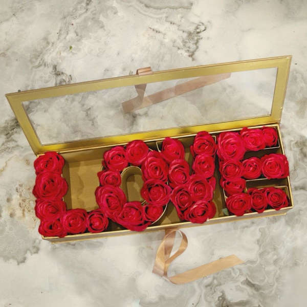 Red roses arranged in a gold box spelling "LOVE"