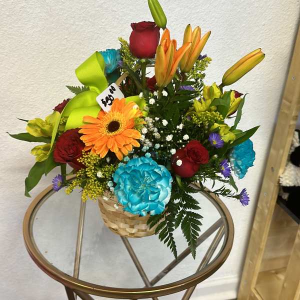 Mixed bouquet in a woven basket with roses, lilies, gerbera daisy, and carnations