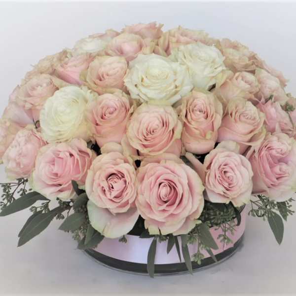 Round bouquet of pale pink and white roses in a low container