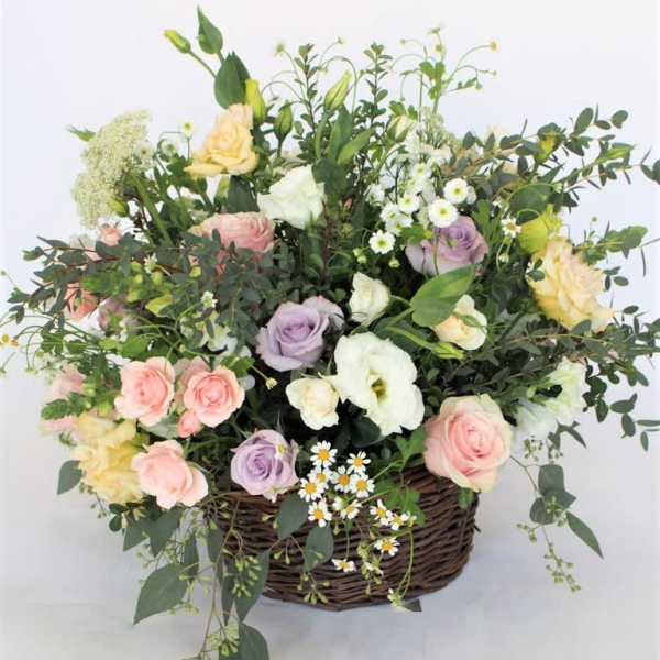 Mixed pastel roses and white blooms in a wicker basket