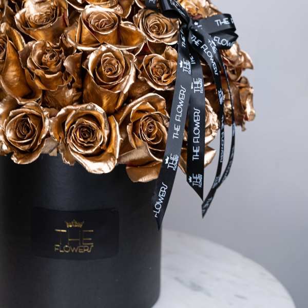 Bouquet of metallic gold roses in a black hat box with ribbon