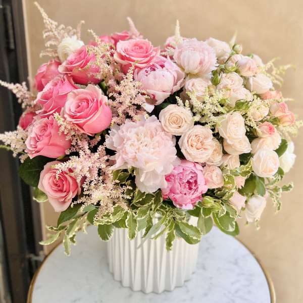 Pink and blush roses arranged in a white vase