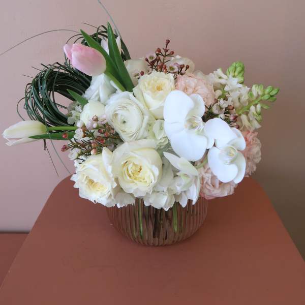 White and blush bouquet with orchids and roses in a glass vase