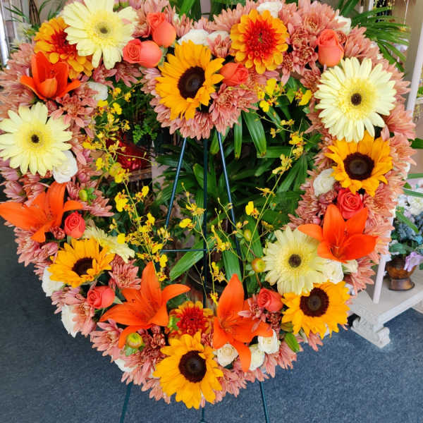 Heart-shaped floral wreath with sunflowers, lilies, roses, and gerbera daisies