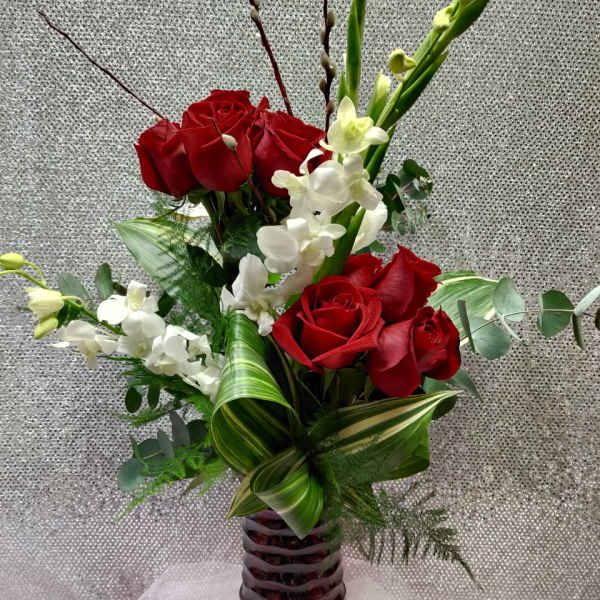 Red roses and white orchids in a tall red glass vase