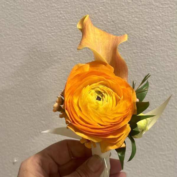Orange ranunculus boutonniere with a calla lily accent