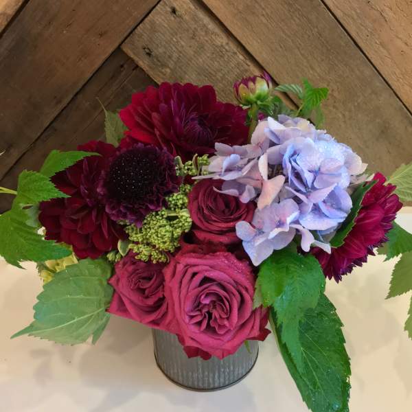 Bouquet of burgundy and pink roses with purple flowers in a metal vase