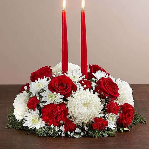 Red candles in a red, white, and green floral centerpiece