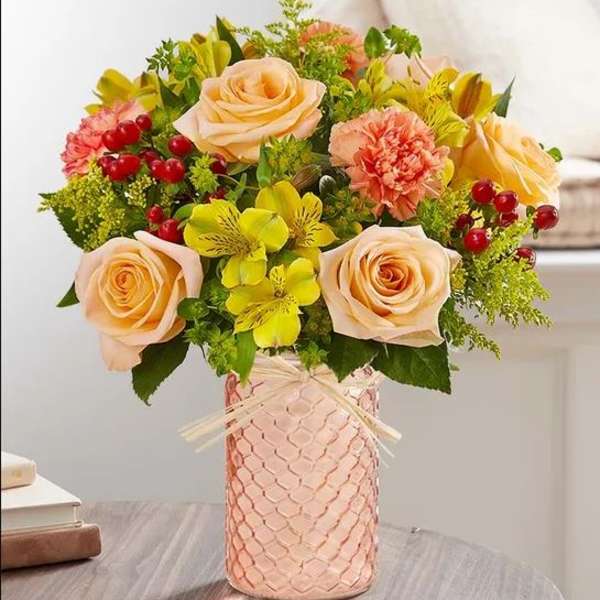 Peach roses and yellow flowers in a pink textured vase