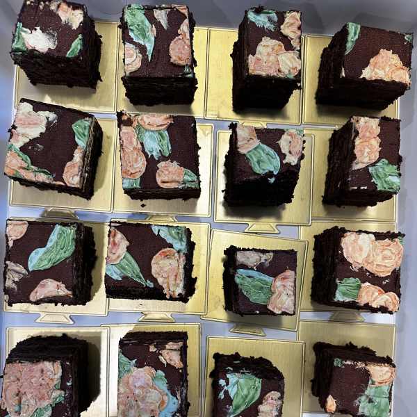 Square chocolate cakes topped with pastel floral frosting on gold boards