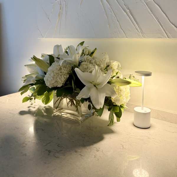 White lilies and hydrangeas in a clear glass vase