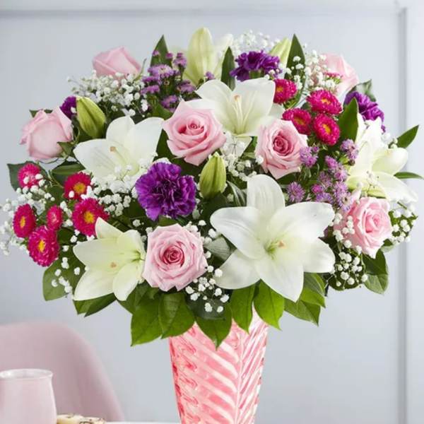 Pink roses and white lilies in a pink glass vase