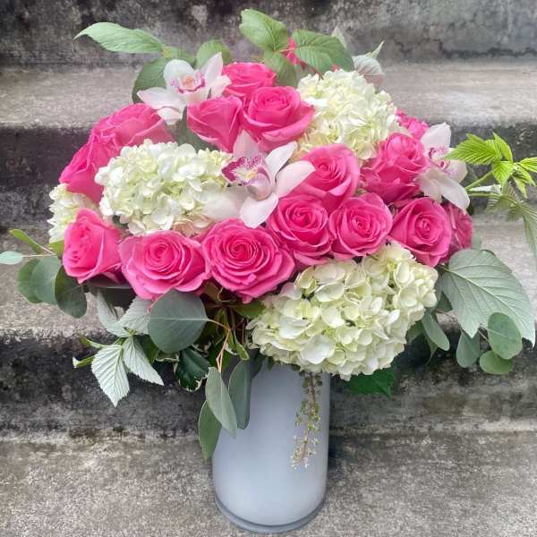 Pink roses and white hydrangeas arranged in a white vase