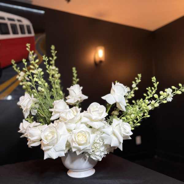 White rose arrangement in a white pedestal vase
