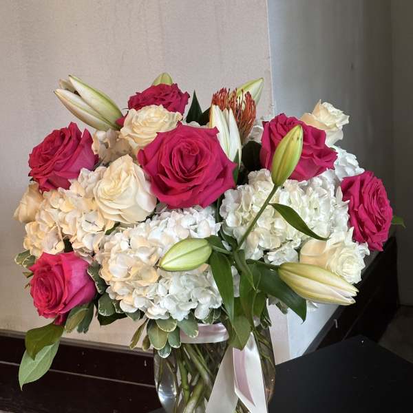 Pink and white roses with lilies and hydrangeas in a glass vase