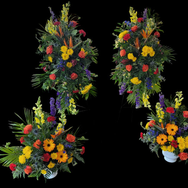 Four colorful floral arrangements with roses and daisies in white urns