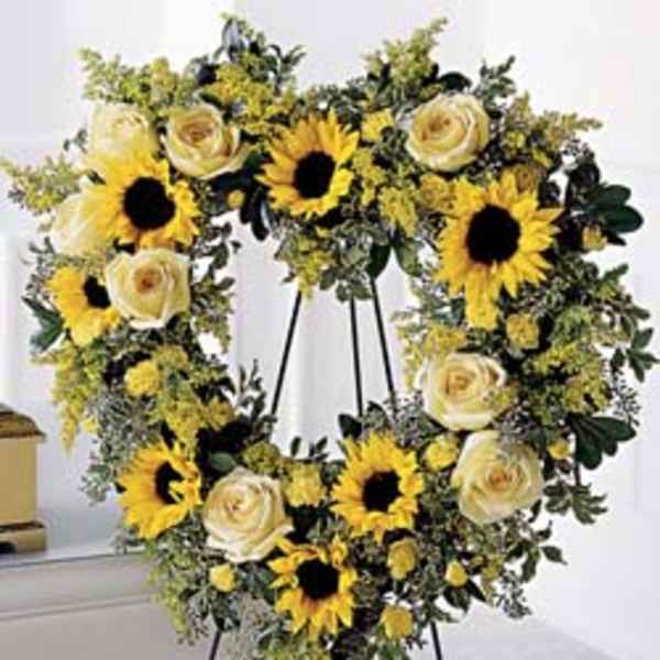 Heart-shaped wreath with sunflowers and cream roses on an easel