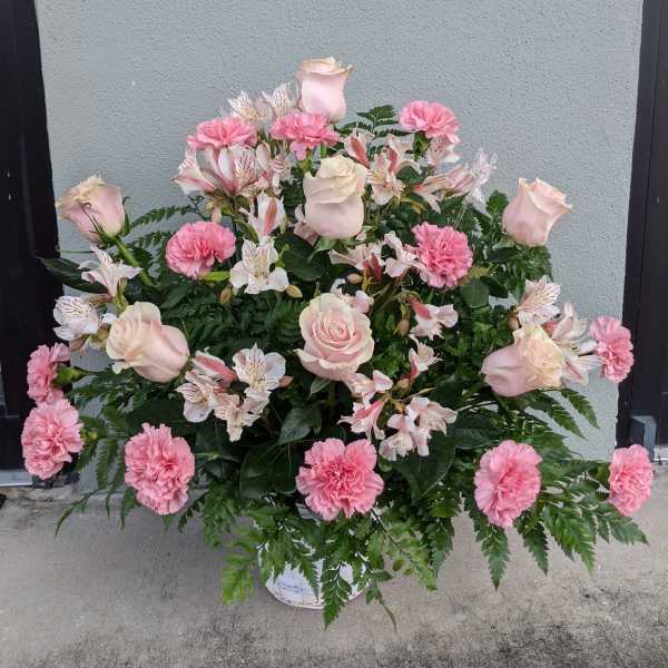 Pink roses and carnations arranged in a white basket.