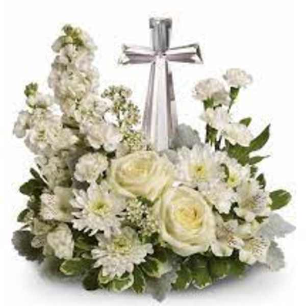 Low white floral arrangement with roses and daisies surrounding a silver cross ornament