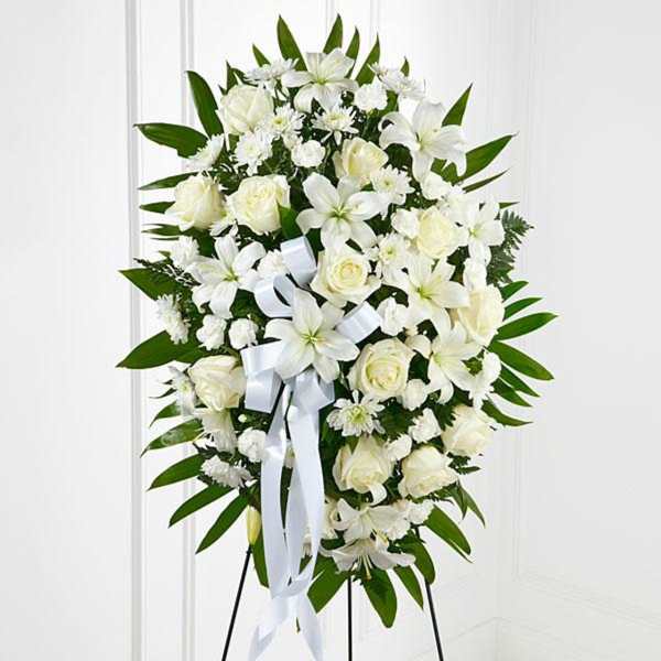White floral standing spray with roses and lilies on an easel