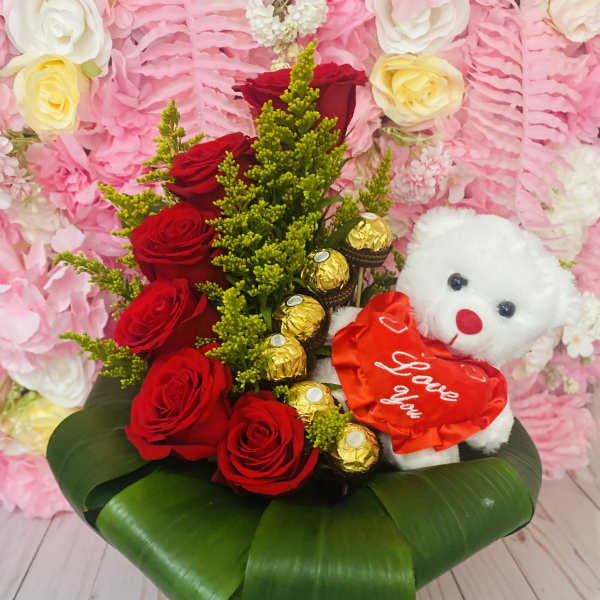 Red roses with chocolates and a teddy bear in a white container