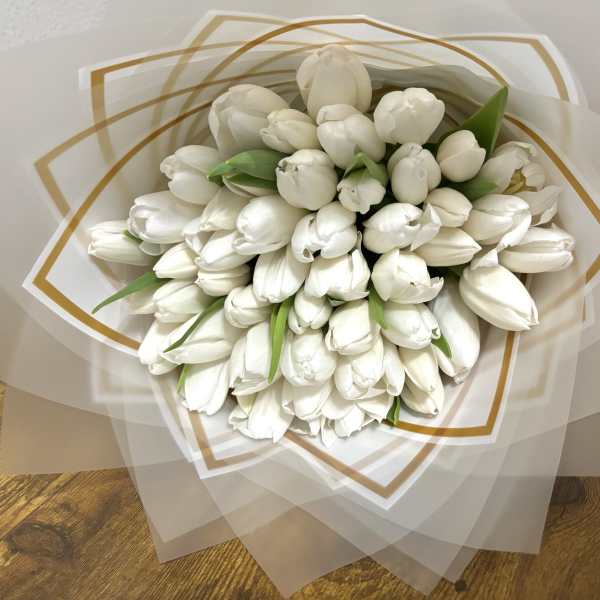 Bouquet of white tulips wrapped in translucent paper