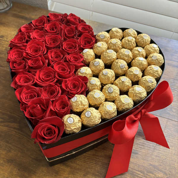 Heart-shaped box with red roses and gold-wrapped chocolates tied with a red ribbon