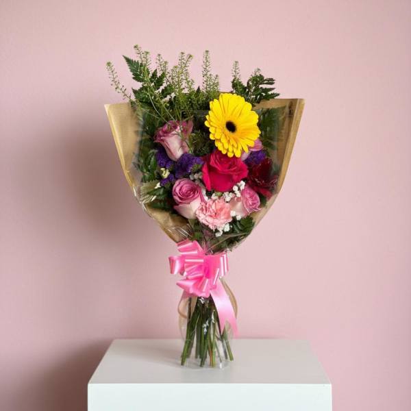 Mixed bouquet with pink and yellow flowers wrapped in clear paper