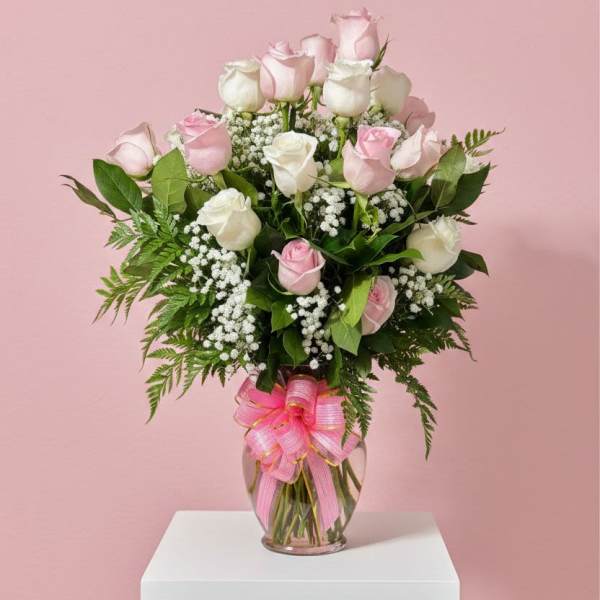 Pink and white roses in a glass vase with a pink ribbon