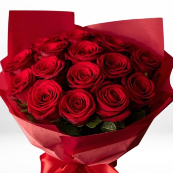 Hand-tied bouquet of red roses wrapped in red paper with a satin bow