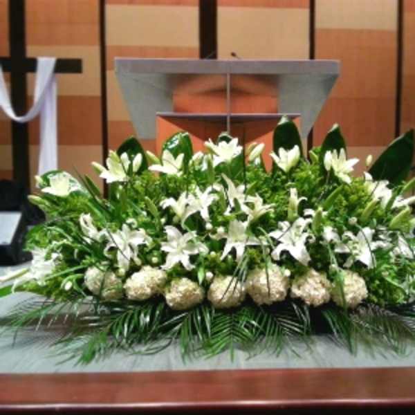 Low, elongated white lily and hydrangea arrangement on a stage in front of a podium